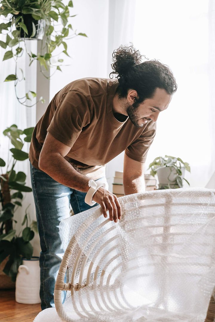 Man with ponytail wrapping wicker furniture in protective material so it's ready to ship