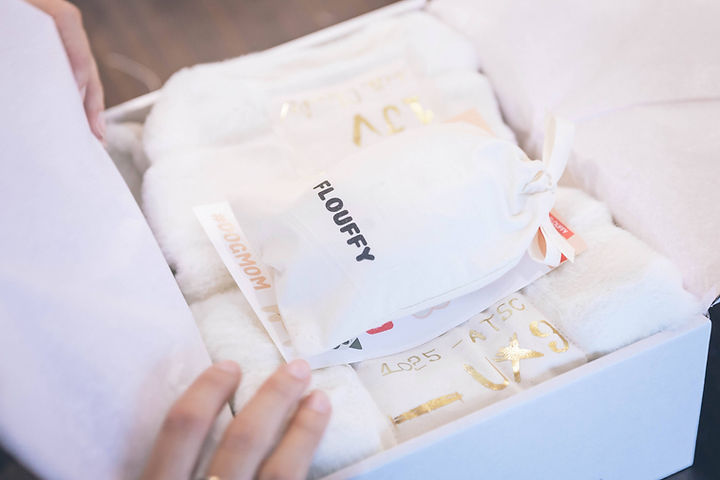 Unboxing experience with custom and eco-friendly white, brand package with logo "FLOUFFY" in black letters. 