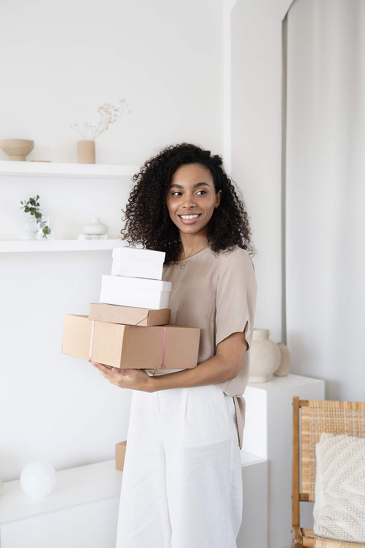 Mixed-race woman holding white and brown flat-rate shipping boxes. 
