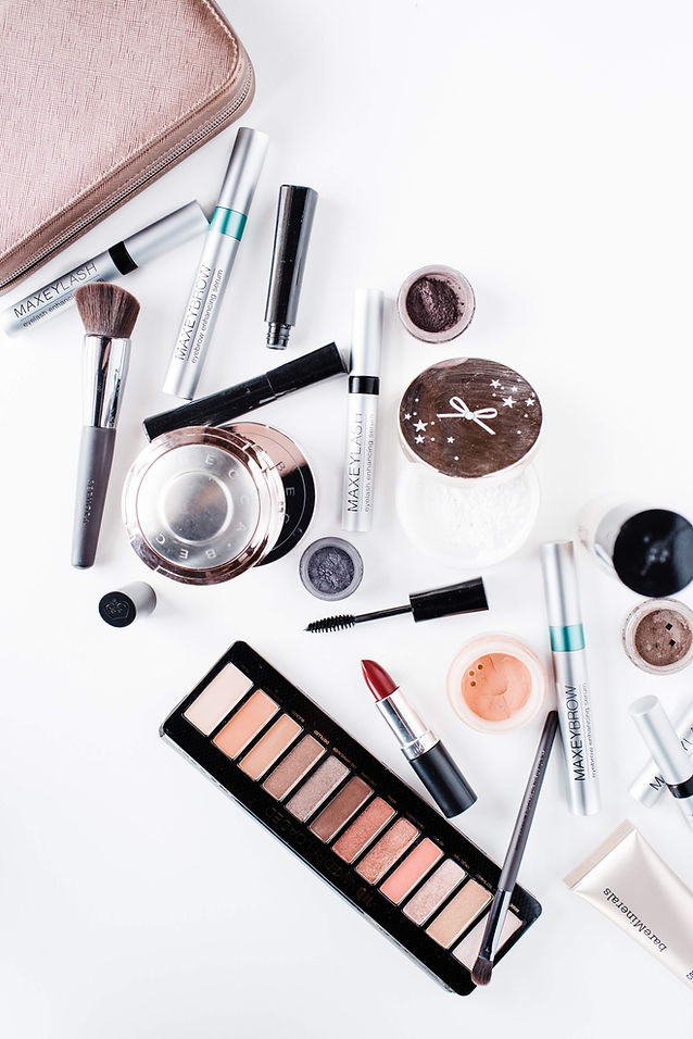 An array of makeup and cosmetics products that are ready to ship against a white background. This includes pastel colored palettes, red lipstick, silver eyeliner bottles and brushes of varying sizes. 